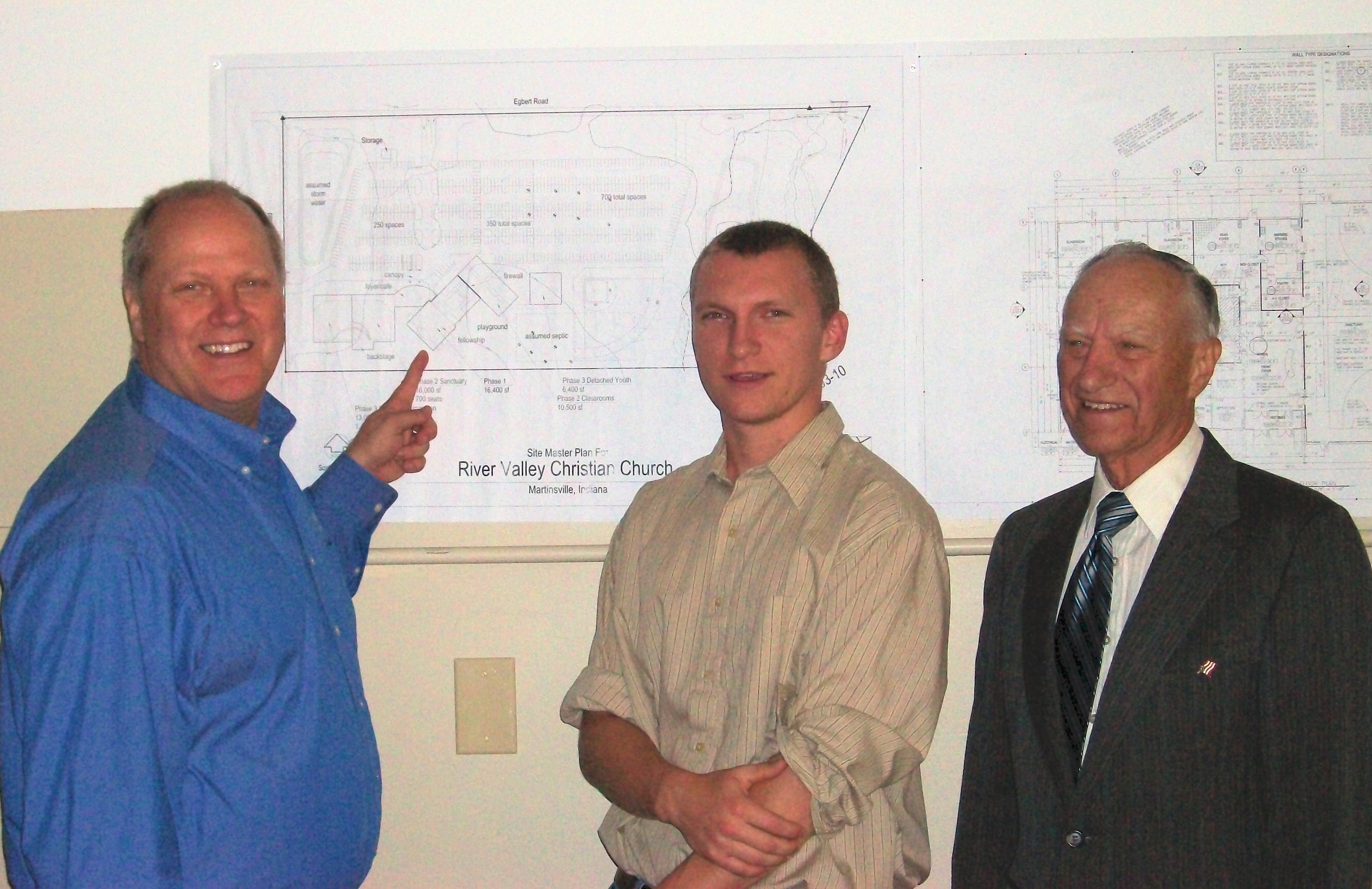 Three generations of preachers with building plans for River Valley Christian Church